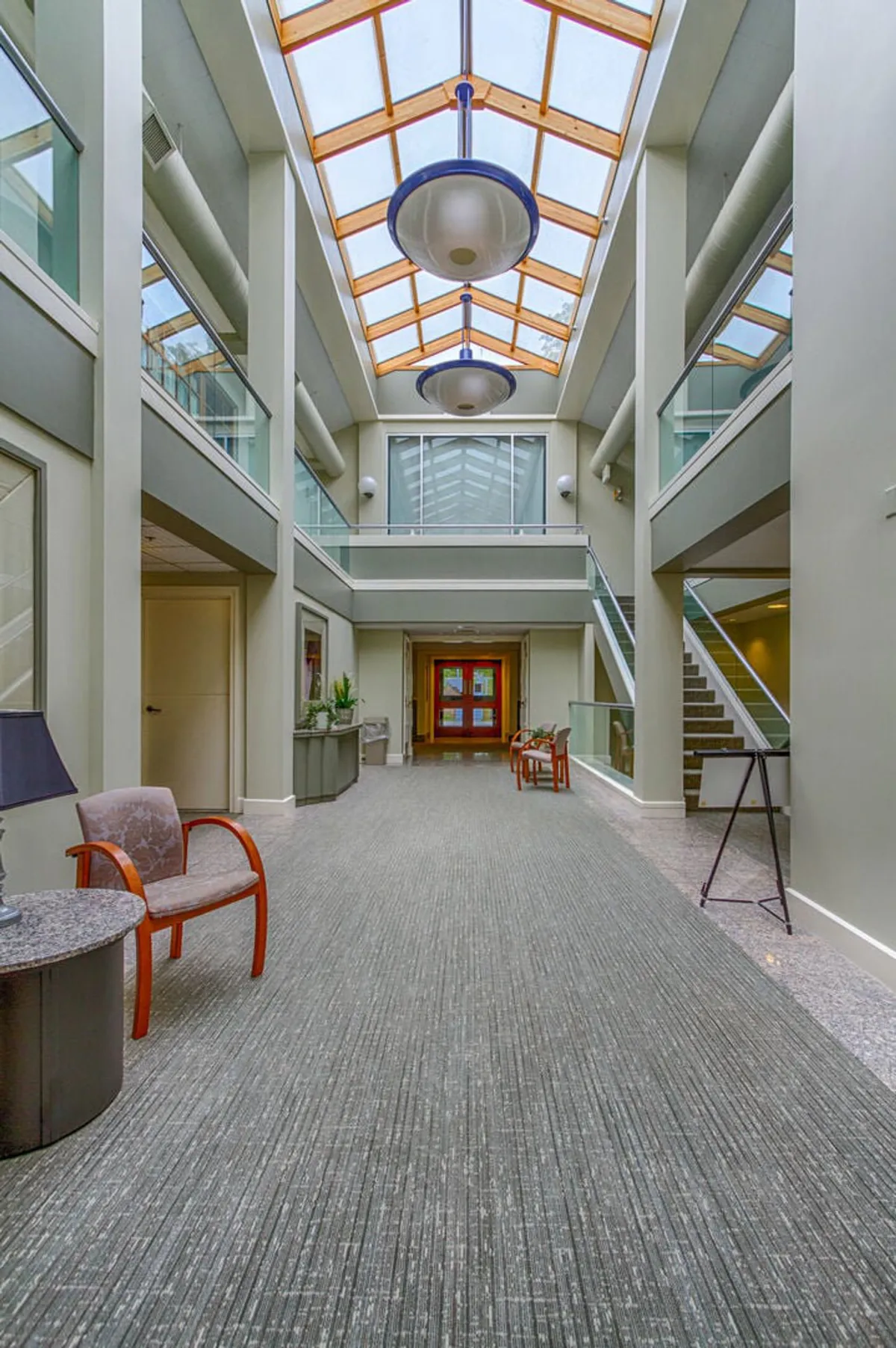 An inviting interior reception area with a large skylight, exposed wooden beams, and a cozy waiting area. The open space feels bright, warm, and welcoming, perfect for greeting guests or waiting for spa appointments.