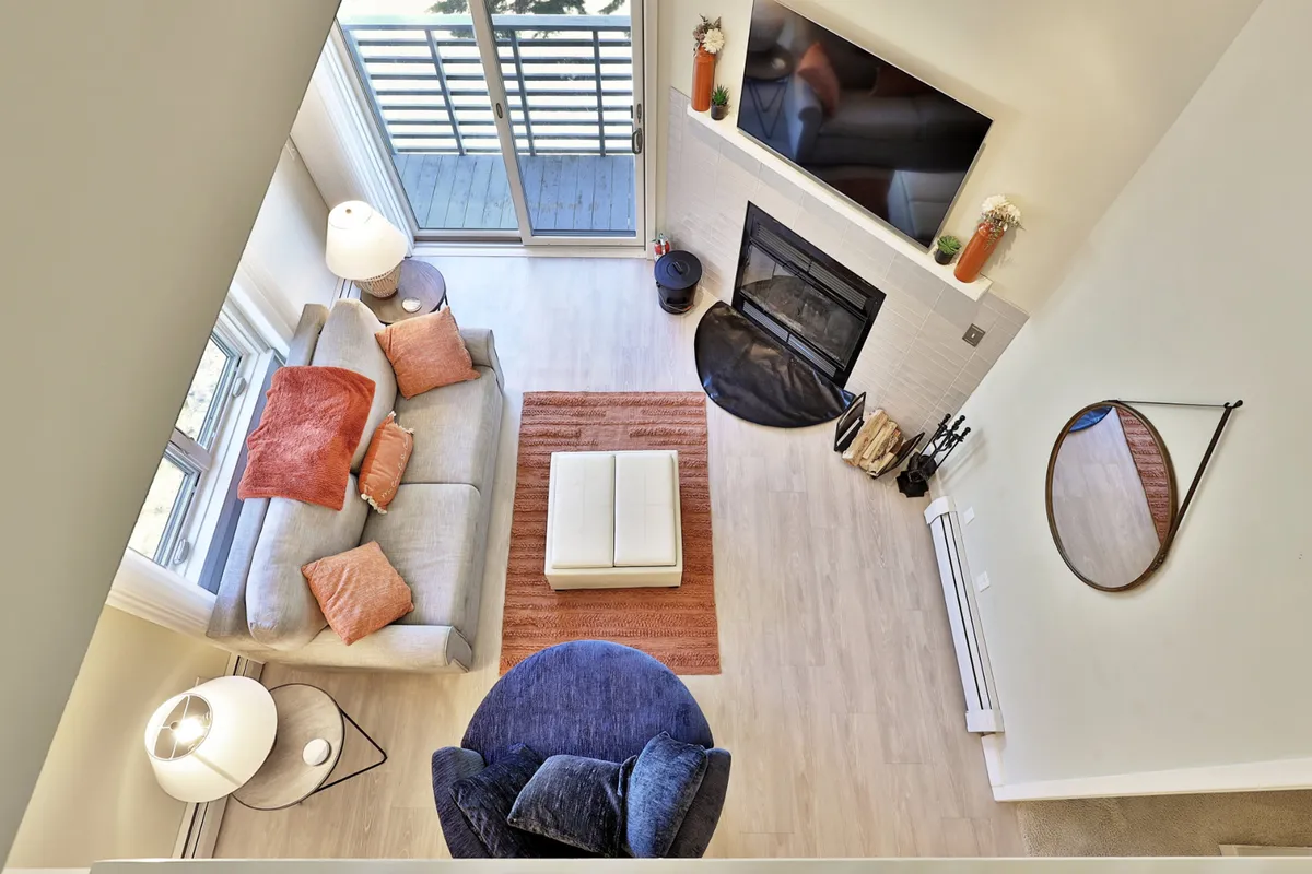 A warm, inviting living area with a sofa adorned with decorative pillows, a round chair, a wood-burning fireplace, a coffee table, and a television. The arrangement encourages relaxation, conversation, and entertainment for guests or family.
